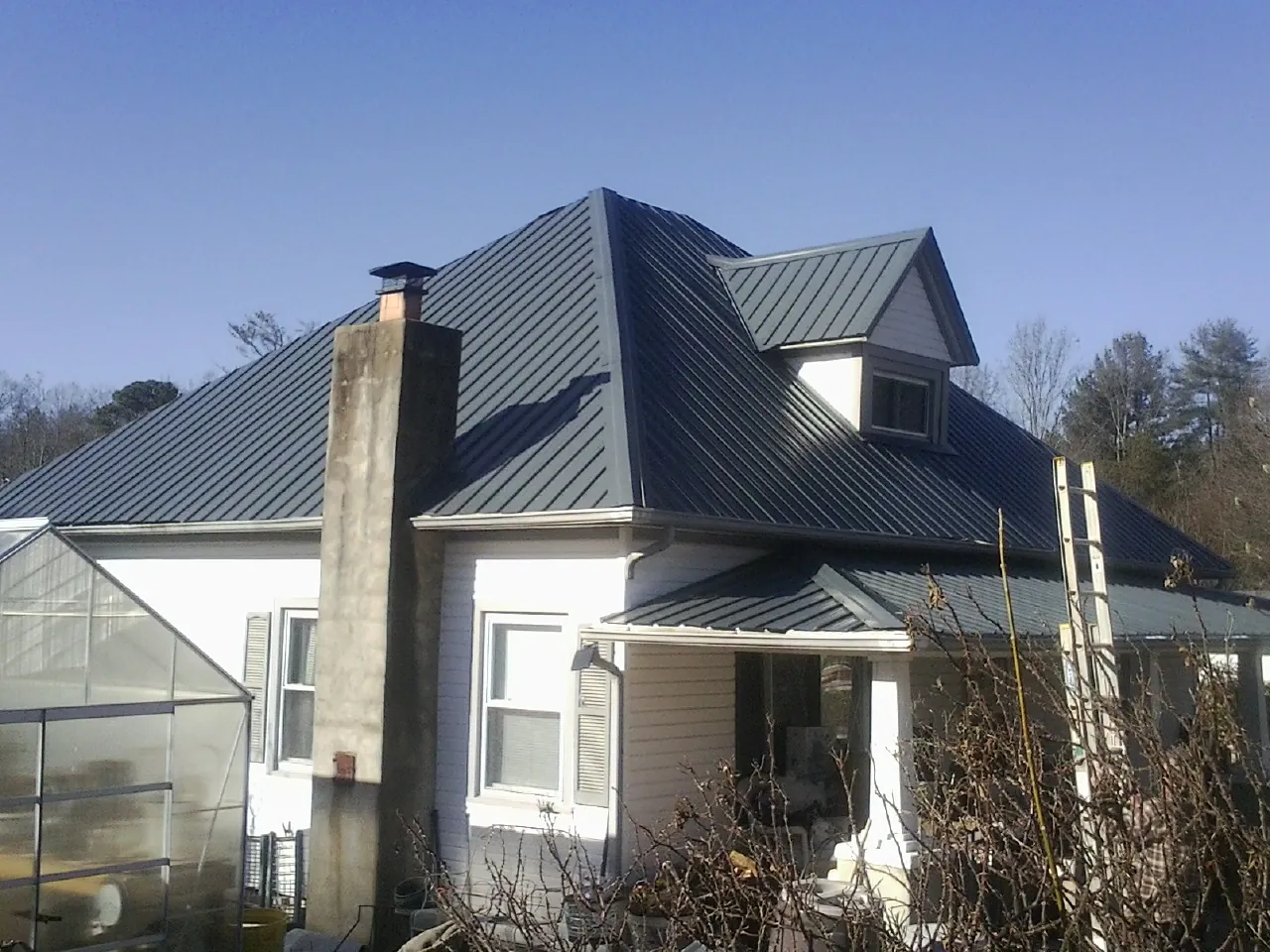 Dark blue standing seam metal roof on a white farmhouse with dormer — Slate & Tile Roof Repair by Roofing Brothers in Stayton