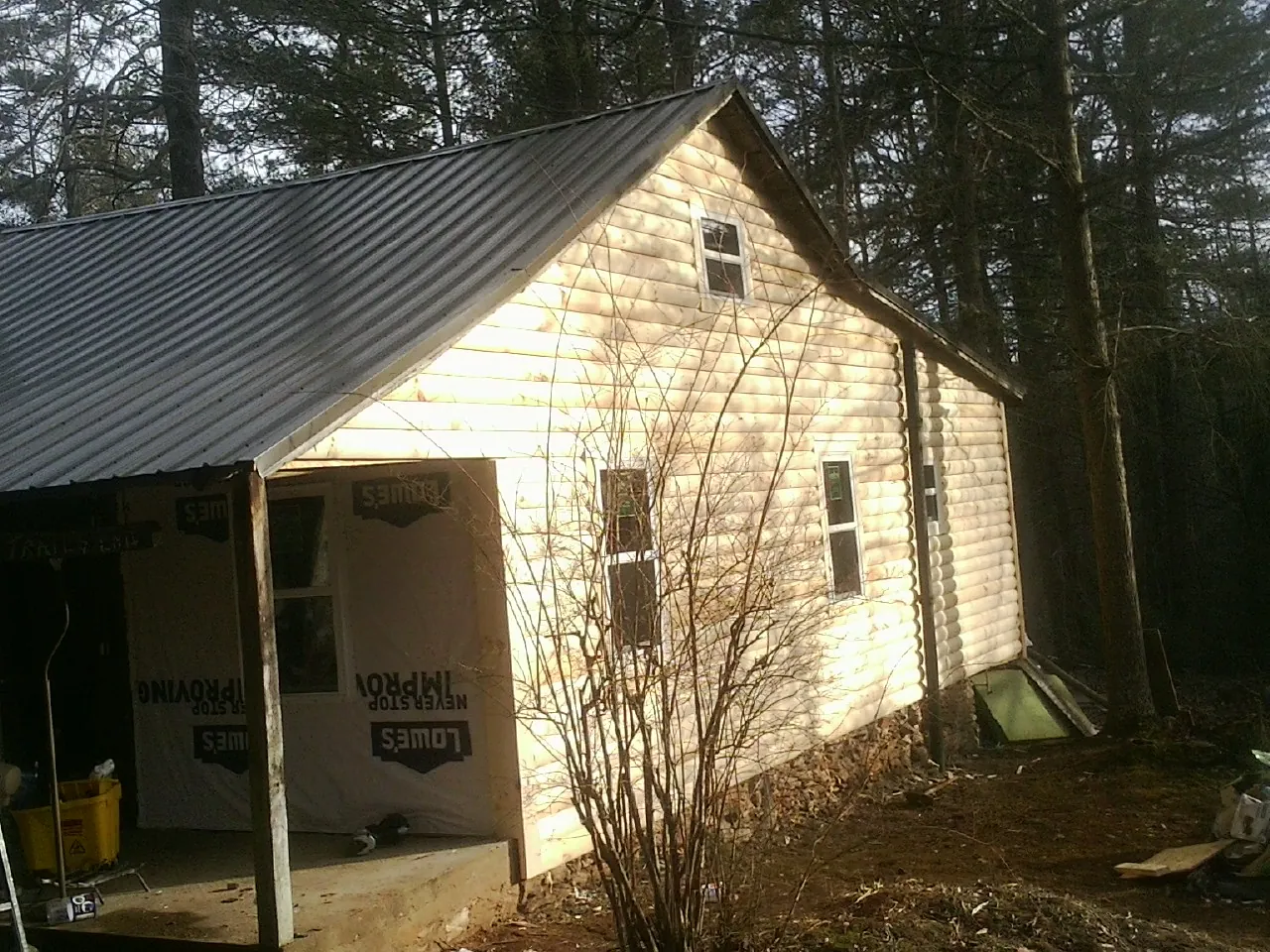 Log siding gable end under a dark metal roof edge in Stayton