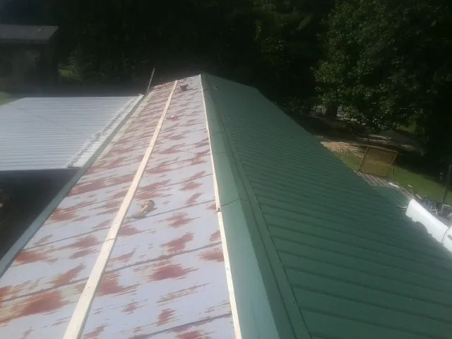 Old rusted panels beside newly installed green metal roofing — Wind Damage Roof Repair by Roofing Brothers in Stayton