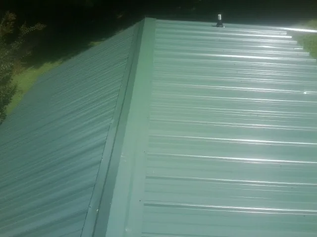 New green metal panels meeting at the ridge of a roof — Flat Roof Repair work by our crew in Stayton