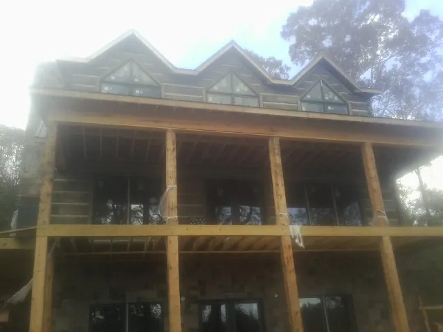 Dormers and porch framing on a large log home under construction — Roof Coating work by our crew in Stayton