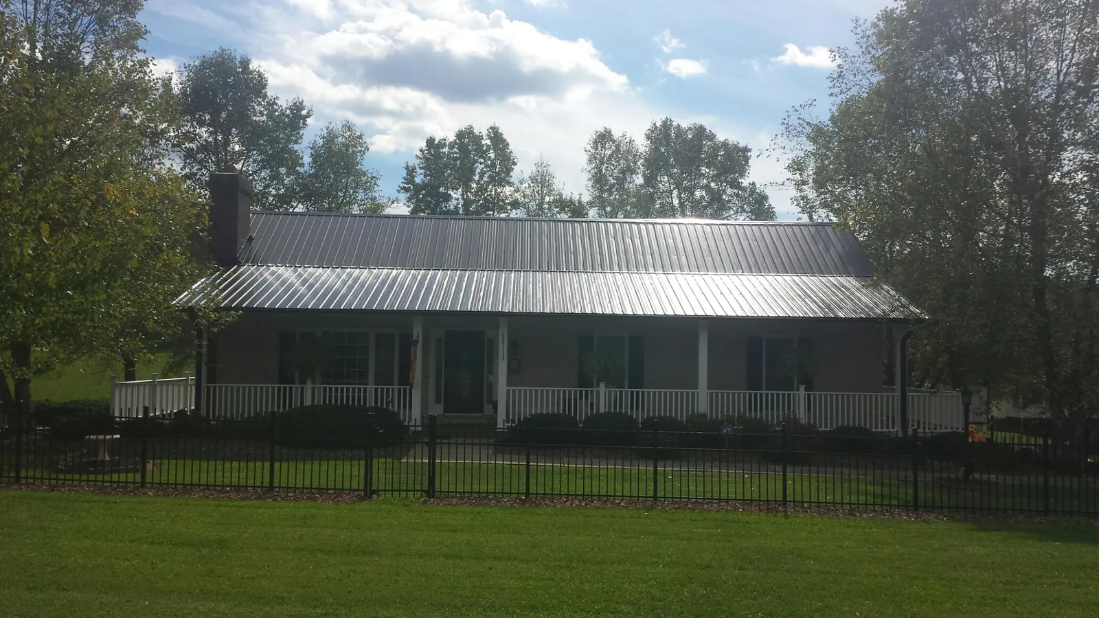 Gray metal roof on a brick ranch with a full width front porch — Gutter Guard Installation work by our crew in Stayton
