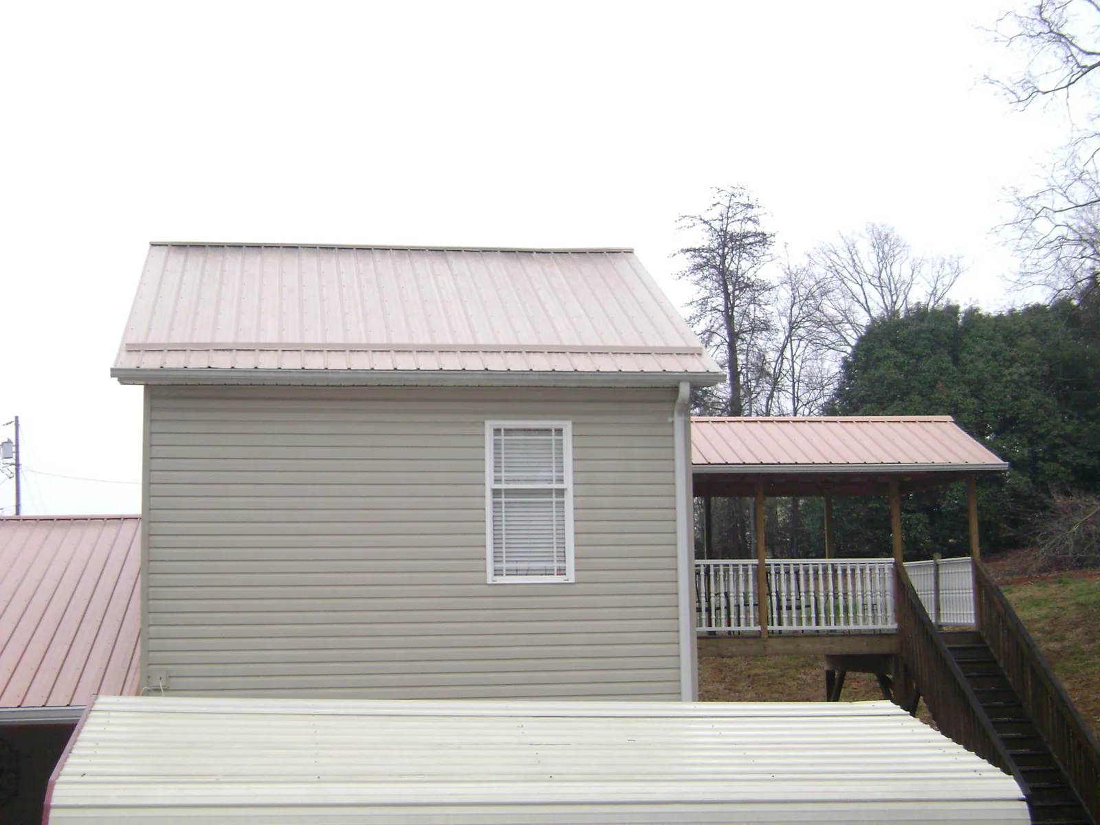 Tan metal roofs on a two story addition and attached porch, from a Roof Replacement job in Stayton