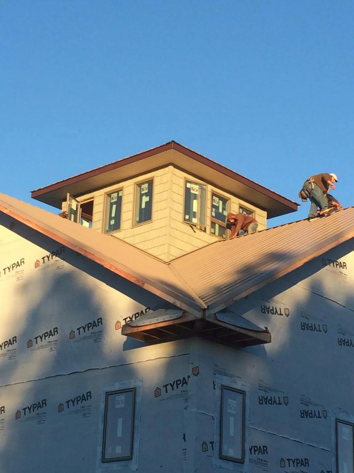 Roofers working around a rooftop cupola on a new metal roof at sunset — Roof Waterproofing in Stayton by Roofing Brothers